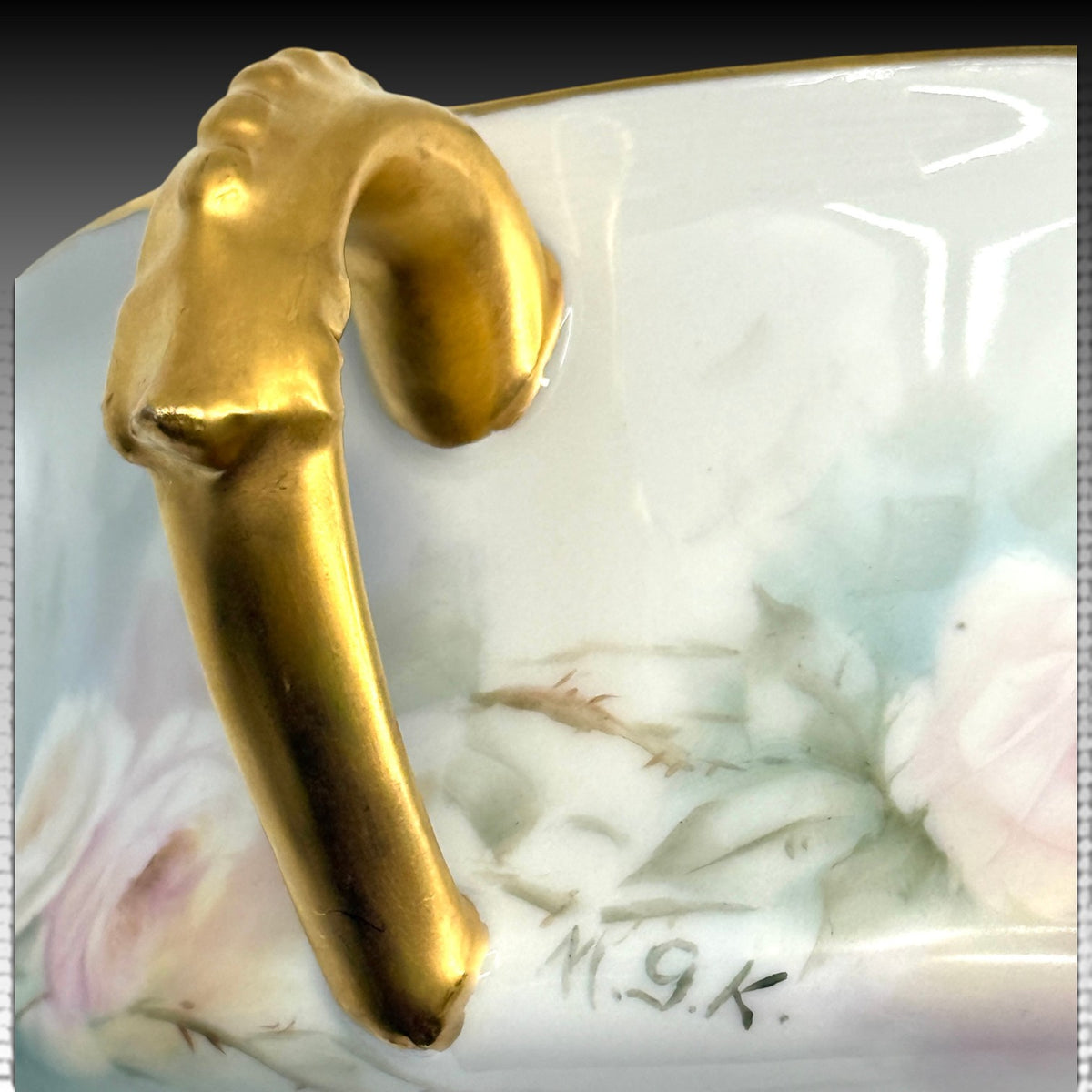 Hand-painted M.G.K. artist signature beside gilded handle